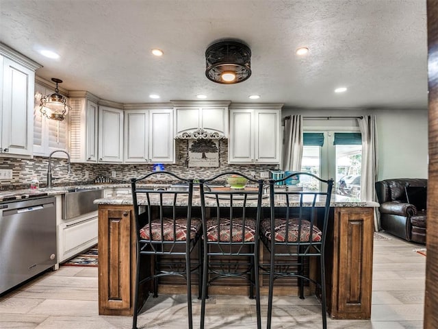 kitchen featuring light stone countertops, a breakfast bar, decorative light fixtures, dishwasher, and a center island