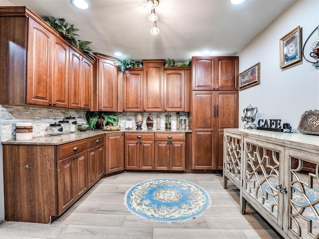 kitchen with light stone countertops, backsplash, and light hardwood / wood-style floors