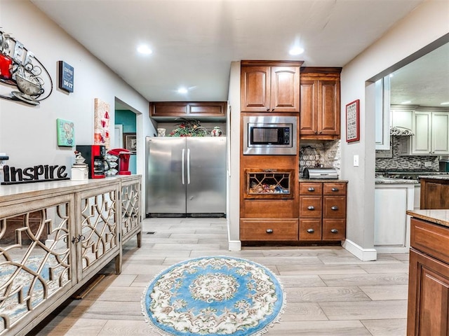 kitchen featuring light hardwood / wood-style floors, light stone counters, appliances with stainless steel finishes, and tasteful backsplash