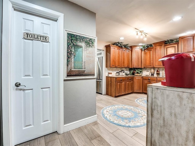 kitchen featuring stainless steel fridge, tasteful backsplash, and light hardwood / wood-style flooring