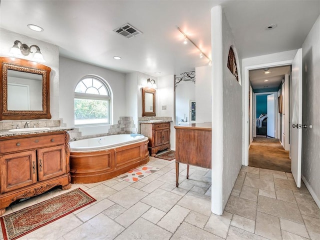 bathroom featuring vanity, a tub to relax in, and rail lighting