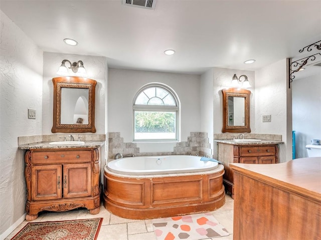 bathroom with tile patterned floors, a washtub, and vanity