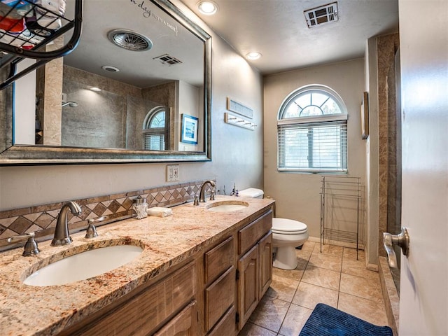 bathroom with tiled shower, vanity, tile patterned flooring, and toilet