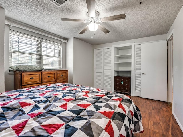 bedroom featuring dark hardwood / wood-style floors, ceiling fan, and a textured ceiling