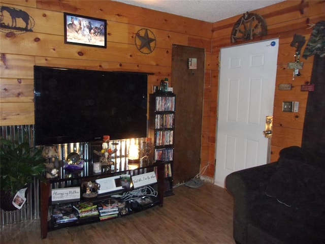 living room featuring wood walls, wood-type flooring, and a textured ceiling