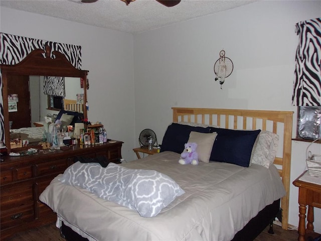 bedroom with ceiling fan, hardwood / wood-style floors, and a textured ceiling