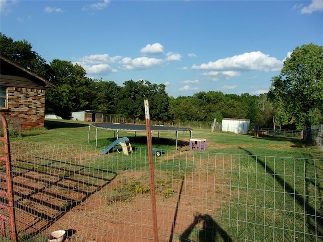 view of yard featuring a trampoline and a shed