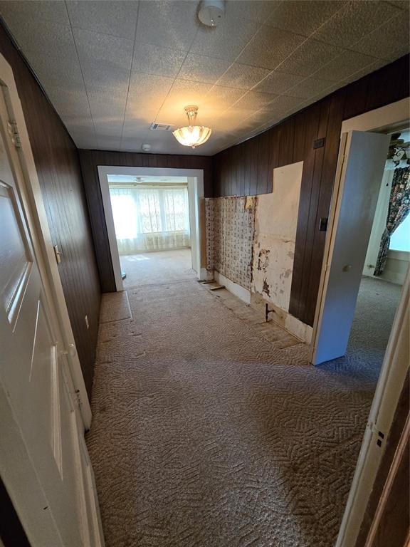 corridor with light colored carpet and wood walls