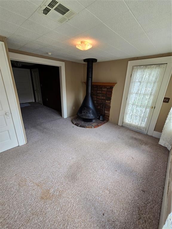 unfurnished living room with carpet floors and a wood stove