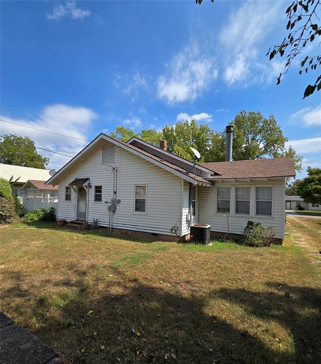 rear view of property featuring a lawn and central AC unit