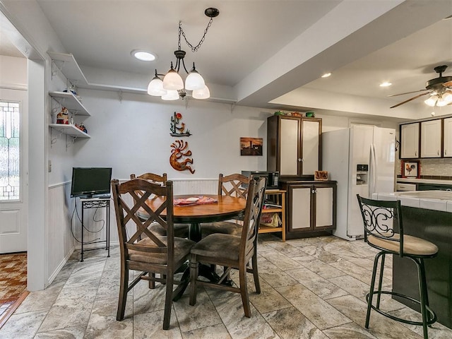 dining space with ceiling fan with notable chandelier