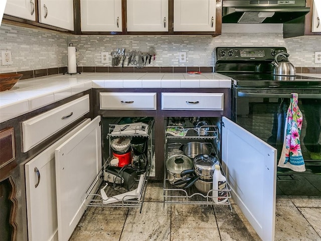 kitchen featuring decorative backsplash, black range with electric stovetop, exhaust hood, tile countertops, and white cabinetry