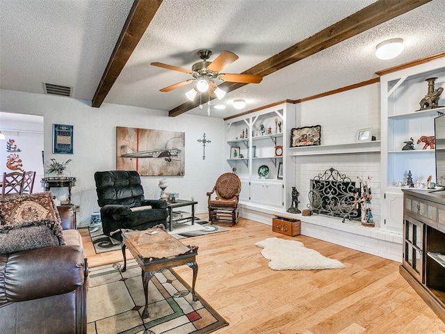 living room featuring a textured ceiling, ceiling fan, beam ceiling, a fireplace, and hardwood / wood-style floors