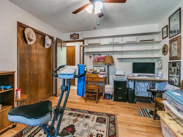 interior space featuring ceiling fan, wood-type flooring, and a textured ceiling