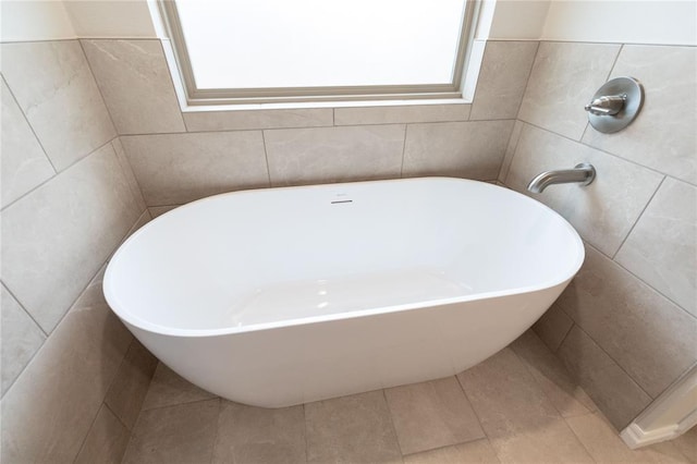 full bathroom with a freestanding tub, tile walls, and tile patterned floors