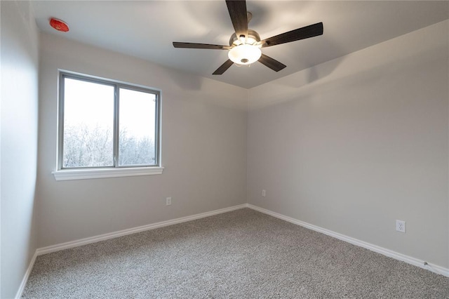 carpeted spare room with a ceiling fan and baseboards