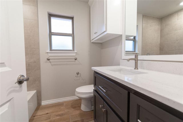 bathroom featuring toilet, wood finished floors, vanity, and baseboards