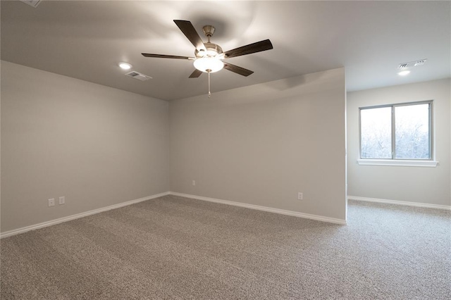 carpeted spare room featuring baseboards, visible vents, and a ceiling fan