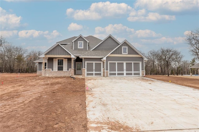 craftsman house featuring brick siding, roof with shingles, board and batten siding, a garage, and driveway