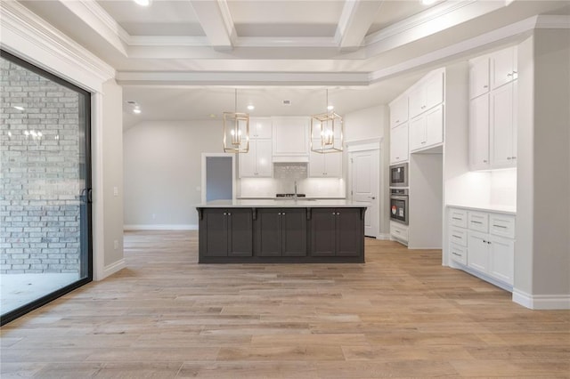 kitchen featuring light wood finished floors, white cabinets, stainless steel appliances, light countertops, and beam ceiling