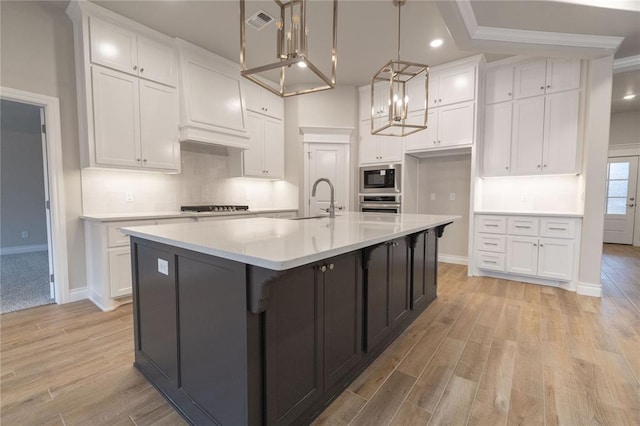 kitchen with visible vents, oven, built in microwave, white cabinetry, and a sink