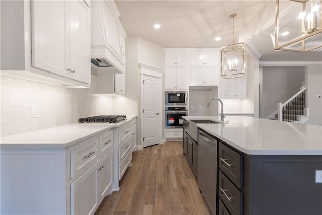 kitchen with stainless steel appliances, a sink, white cabinetry, and custom range hood