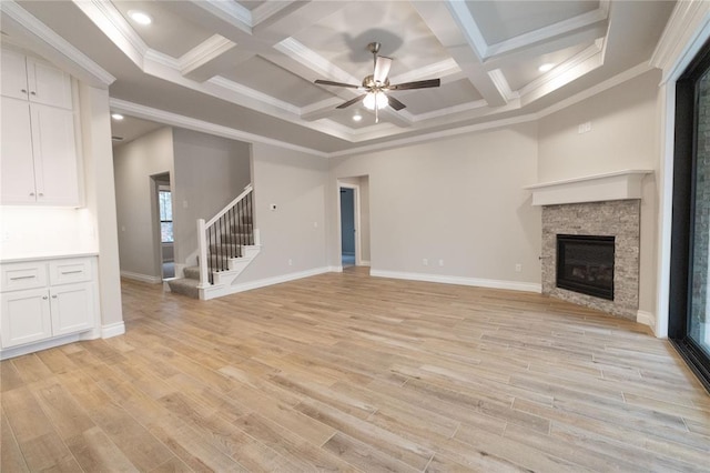 unfurnished living room with light wood-style floors, stairs, a ceiling fan, and a stone fireplace