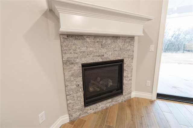 room details with wood finished floors, a glass covered fireplace, and baseboards