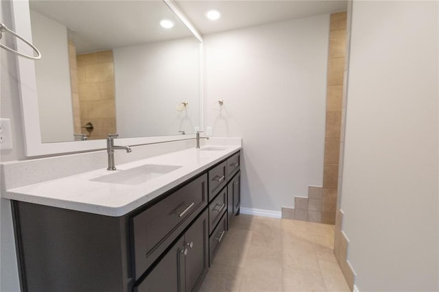 full bath featuring double vanity, tile patterned flooring, a sink, and baseboards