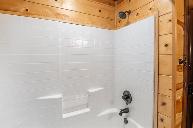 bathroom with shower / washtub combination and wood walls