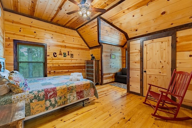 bedroom featuring light hardwood / wood-style flooring, vaulted ceiling, ceiling fan, and wooden walls