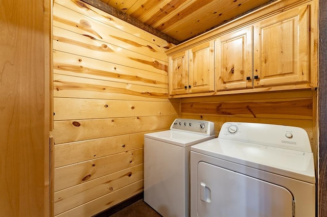 washroom with cabinets, washer and dryer, wood ceiling, and wood walls