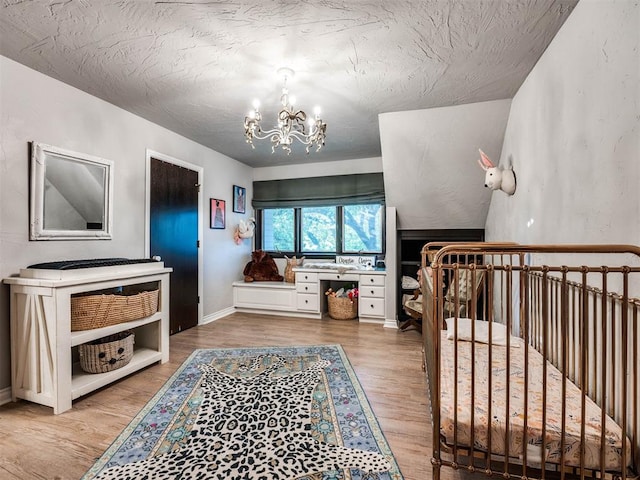 bedroom featuring wood-type flooring, a textured ceiling, vaulted ceiling, and a notable chandelier