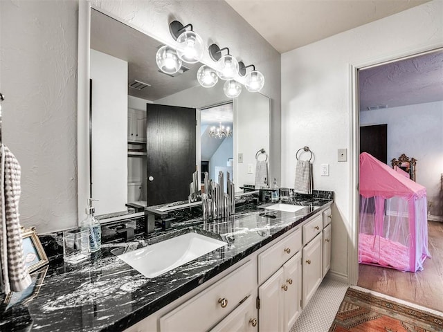 bathroom with double vanity, wood finished floors, a sink, and an inviting chandelier