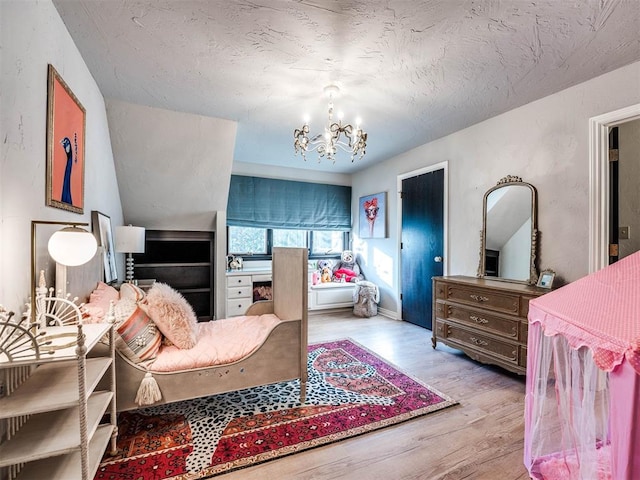 bedroom featuring an inviting chandelier, a textured ceiling, and wood finished floors