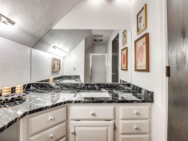 full bath with a shower stall, vaulted ceiling, a textured ceiling, and vanity