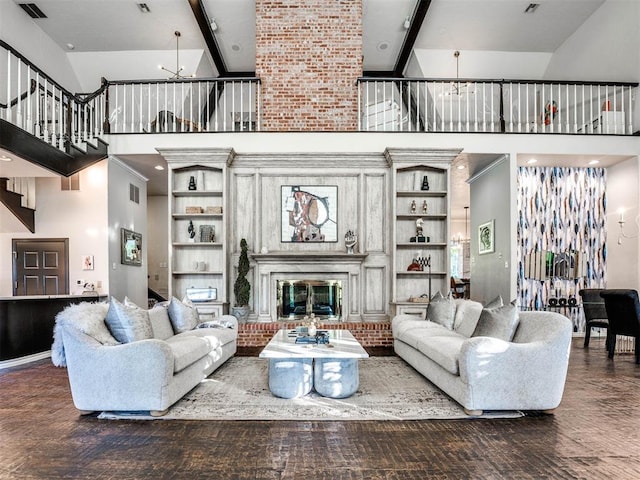 living room with built in shelves, a brick fireplace, beamed ceiling, high vaulted ceiling, and a notable chandelier