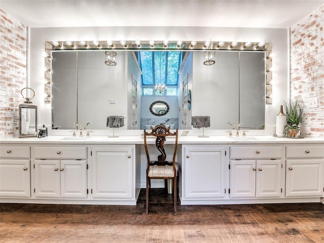 bathroom featuring wood-type flooring, vanity, and brick wall