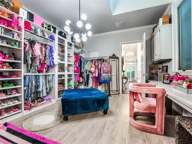 spacious closet with light hardwood / wood-style floors and a chandelier