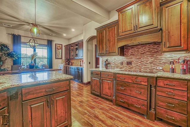 kitchen with light stone countertops, premium range hood, decorative light fixtures, black electric stovetop, and light wood-type flooring