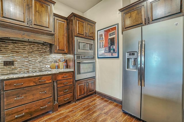 kitchen with tasteful backsplash, light stone countertops, dark hardwood / wood-style floors, and appliances with stainless steel finishes