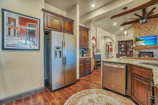 kitchen featuring light stone countertops, appliances with stainless steel finishes, dark hardwood / wood-style flooring, ceiling fan, and lofted ceiling with beams