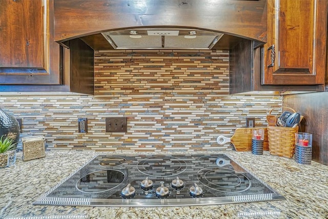 kitchen with decorative backsplash, gas cooktop, light stone counters, and exhaust hood