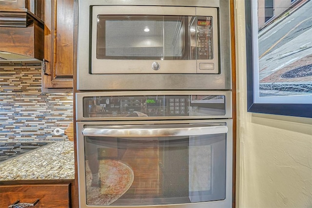 room details with decorative backsplash, stainless steel appliances, and light stone countertops