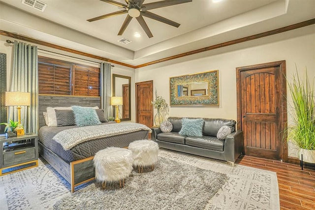 bedroom featuring wood-type flooring, a raised ceiling, and ceiling fan