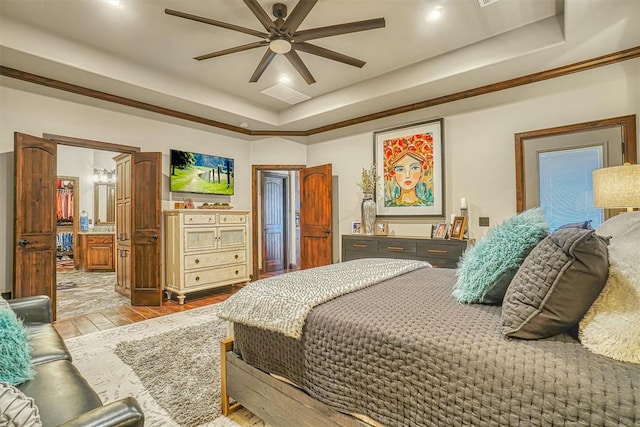 bedroom featuring a tray ceiling, ceiling fan, crown molding, and ensuite bathroom