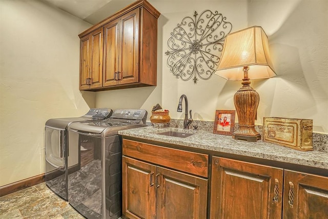 clothes washing area with washer and dryer, sink, and cabinets