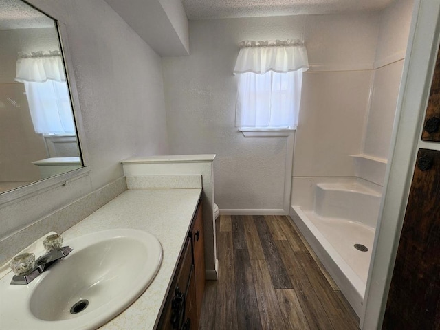 bathroom with vanity, wood-type flooring, a textured ceiling, and walk in shower