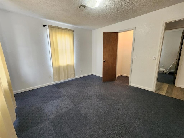 unfurnished bedroom featuring dark colored carpet and a textured ceiling