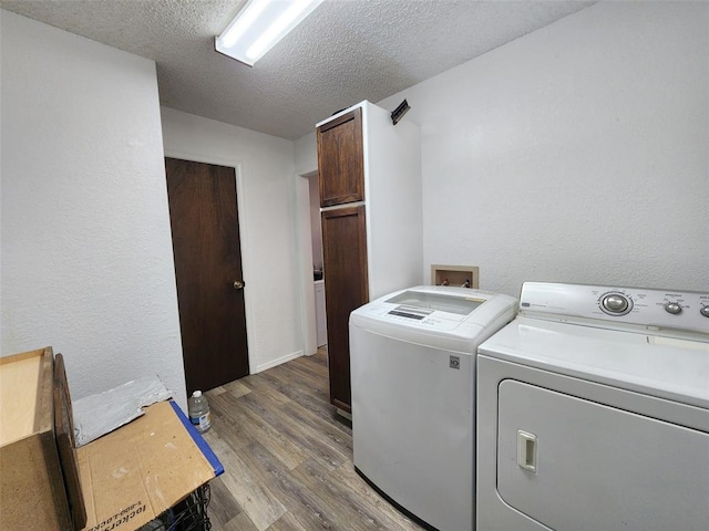 laundry room with cabinets, a textured ceiling, washing machine and dryer, and dark wood-type flooring